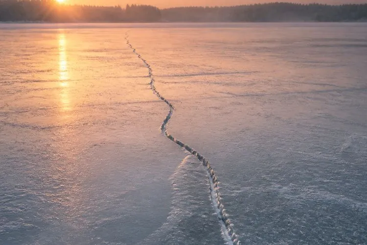 A single crack running across a frozen lake at winter dawn - January split into two zodiac seasons